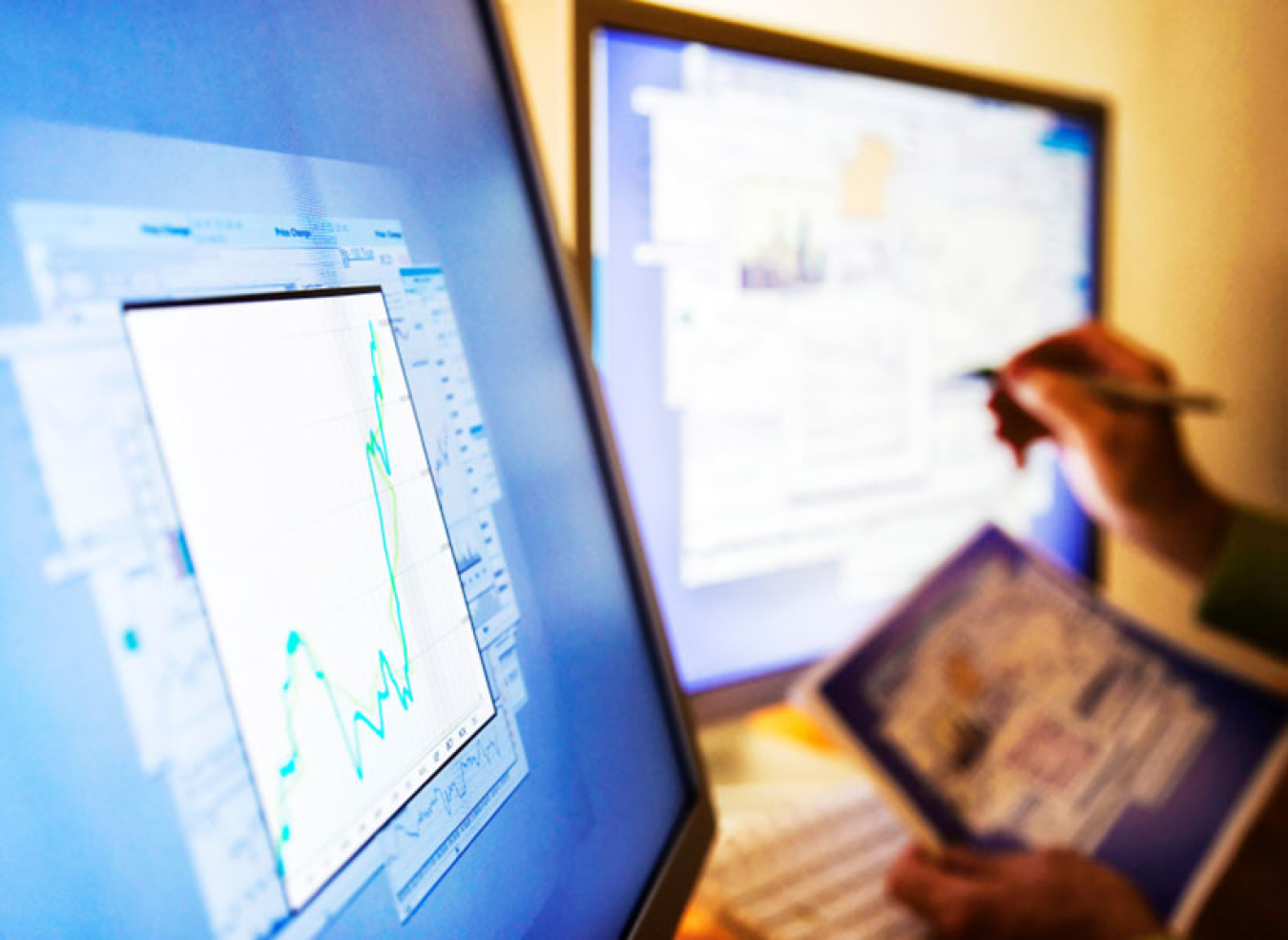 Two hands pointing at computer screens.